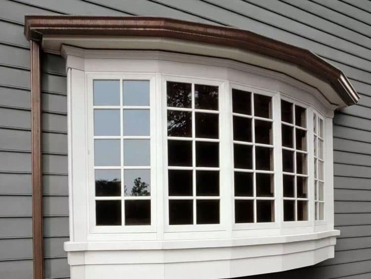 New bow window with divided-light grilles and a copper roof on a gray-sided home